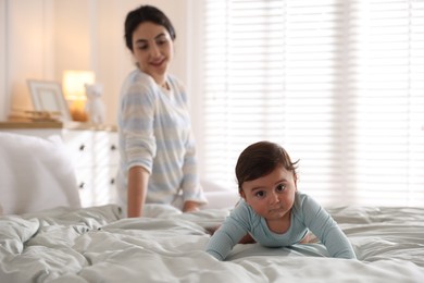 Photo of Mother with her cute little baby on bed indoors, selective focus
