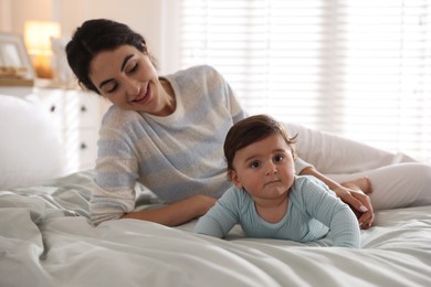 Photo of Mother with her cute little baby on bed indoors