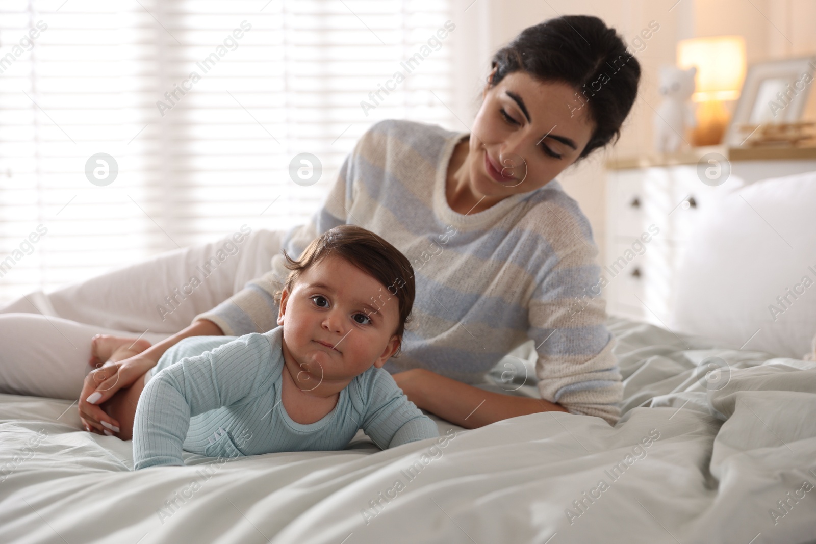 Photo of Mother with her cute little baby on bed indoors