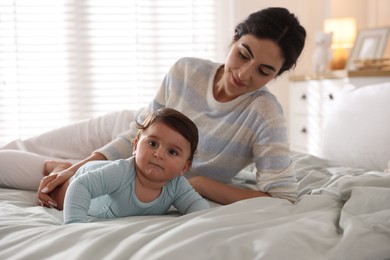 Photo of Mother with her cute little baby on bed indoors