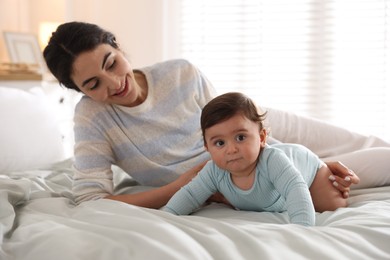 Photo of Mother with her cute little baby on bed indoors