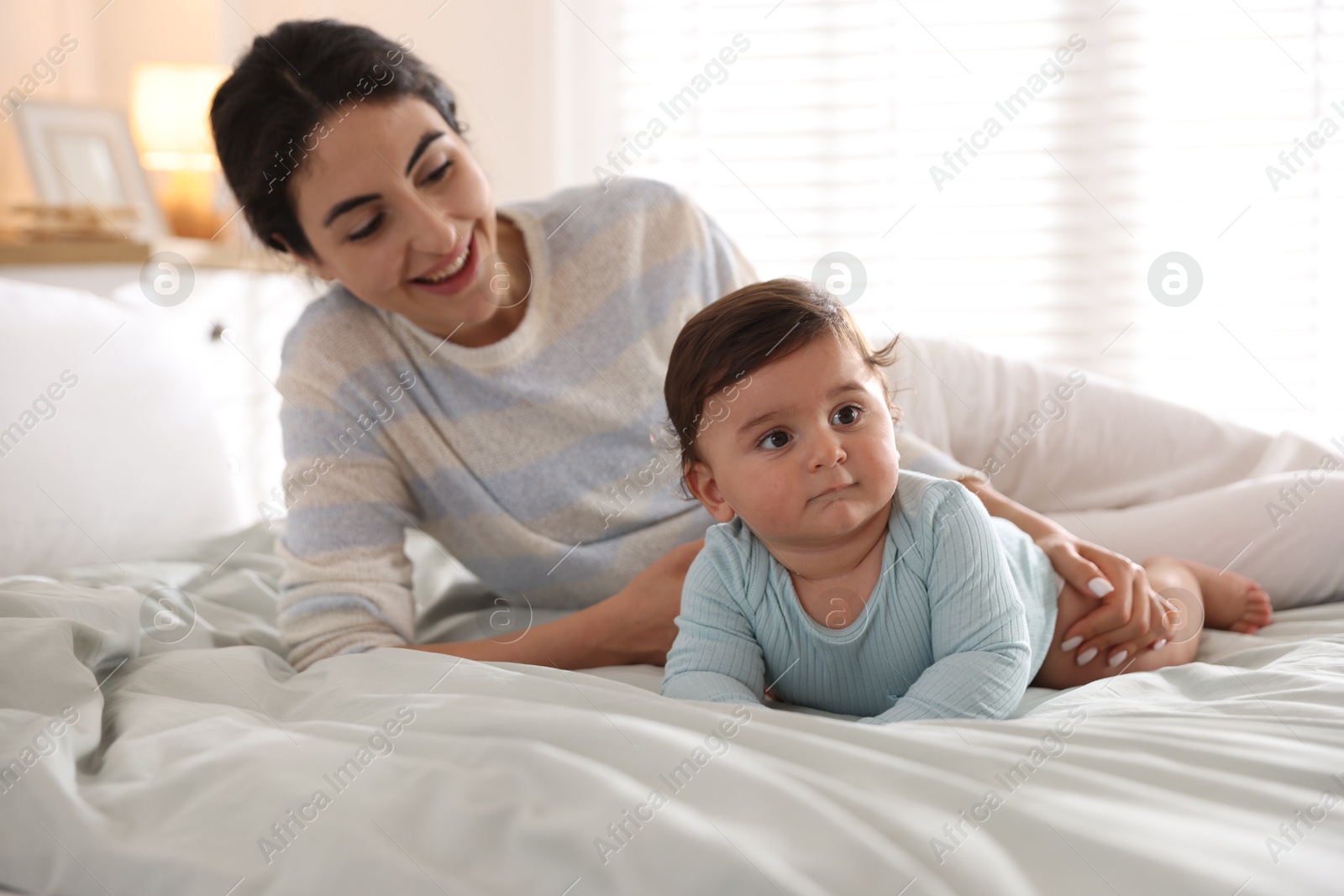 Photo of Mother with her cute little baby on bed indoors