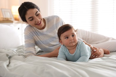 Photo of Mother with her cute little baby on bed indoors