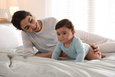 Photo of Mother with her cute little baby on bed indoors