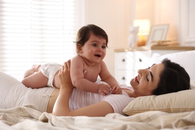 Photo of Mother with her cute little baby on bed indoors