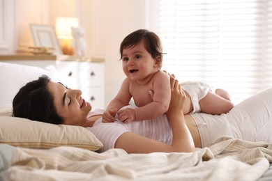 Photo of Mother with her cute little baby on bed indoors