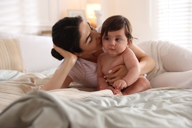 Photo of Mother with her cute little baby on bed indoors
