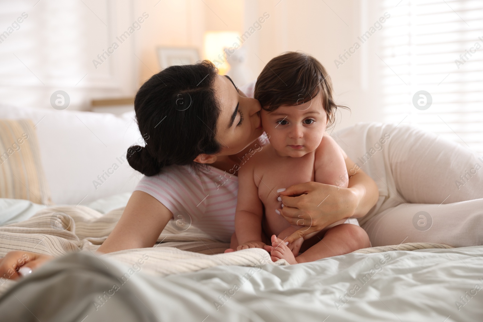 Mother with her cute little baby on bed indoors Photo of Mother with her cute little baby on bed indoors