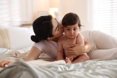 Photo of Mother with her cute little baby on bed indoors