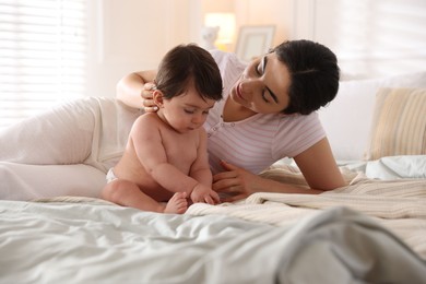 Photo of Mother with her cute little baby on bed indoors