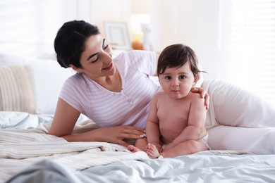Photo of Mother with her cute little baby on bed indoors