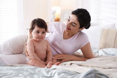 Photo of Mother with her cute little baby on bed indoors