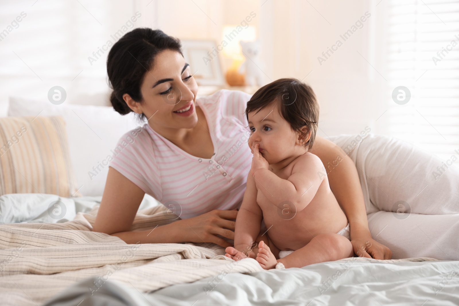 Mother with her cute little baby on bed indoors Photo of Mother with her cute little baby on bed indoors