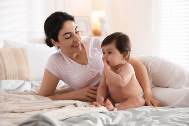 Photo of Mother with her cute little baby on bed indoors