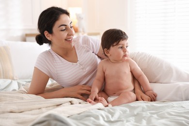 Photo of Mother with her cute little baby on bed indoors