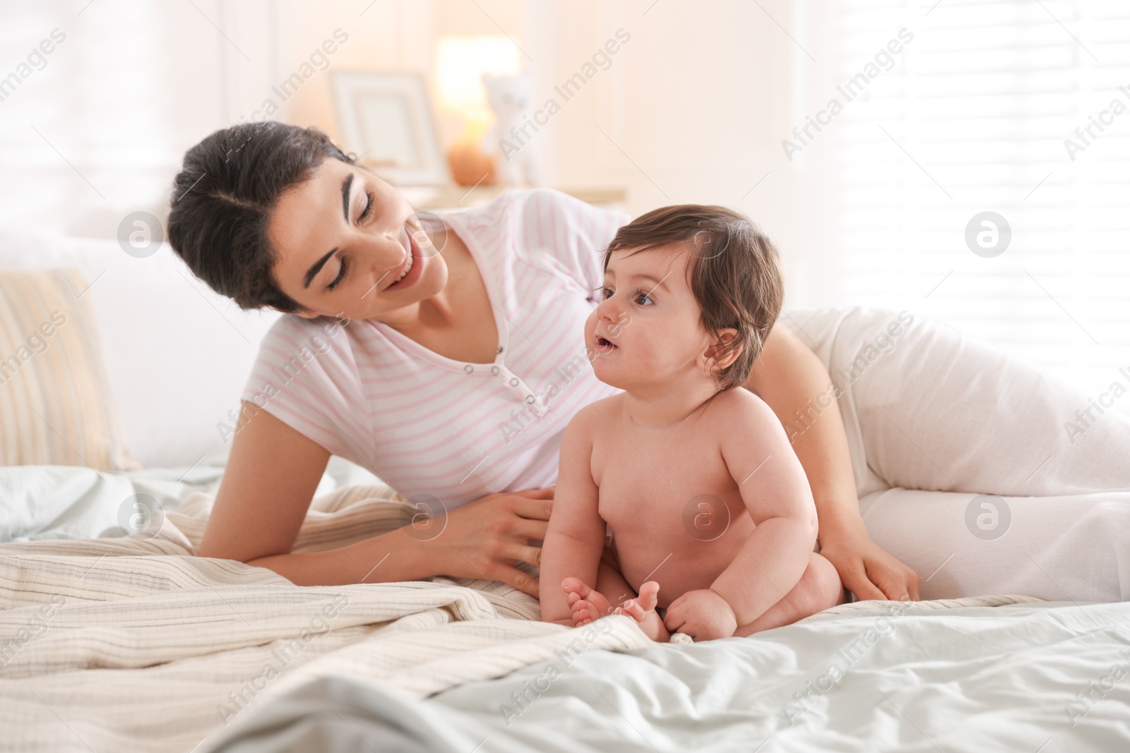 Mother with her cute little baby on bed indoors Photo of Mother with her cute little baby on bed indoors