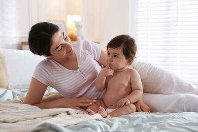 Photo of Mother with her cute little baby on bed indoors