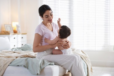 Photo of Mother with her cute little baby on bed indoors