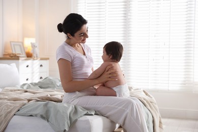 Photo of Mother with her cute little baby on bed indoors