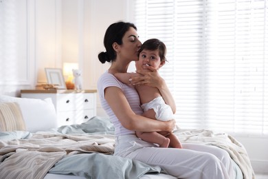 Photo of Mother with her cute little baby on bed indoors