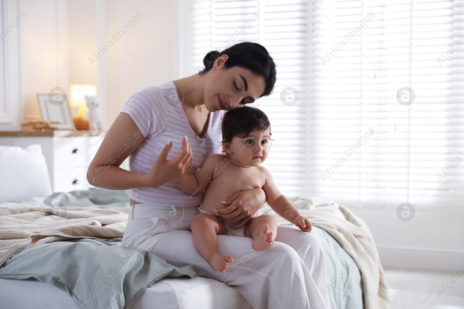 Mother with her cute little baby on bed indoors Photo of Mother with her cute little baby on bed indoors
