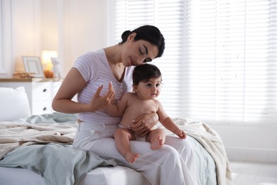 Photo of Mother with her cute little baby on bed indoors