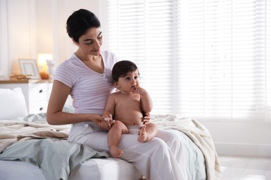 Photo of Mother with her cute little baby on bed indoors
