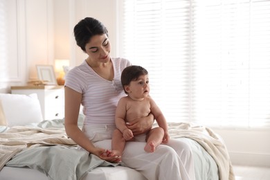 Photo of Mother with her cute little baby on bed indoors