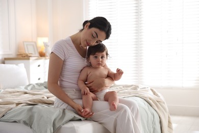 Photo of Mother with her cute little baby on bed indoors