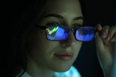 Photo of Young woman wearing glasses with reflection on dark background, closeup