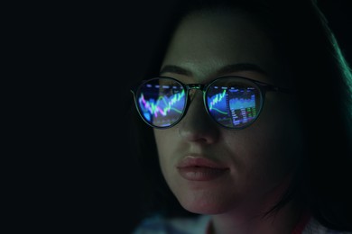 Photo of Young woman wearing glasses with reflection on dark background, closeup