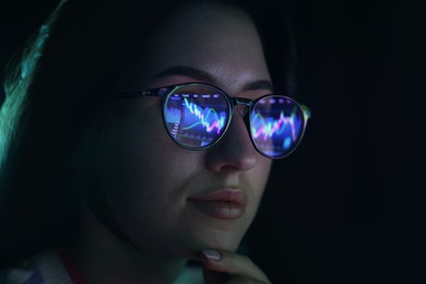 Photo of Young woman wearing glasses with reflection on dark background, closeup