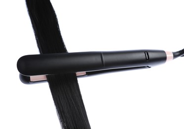 Photo of Straightener with black hair lock isolated on white