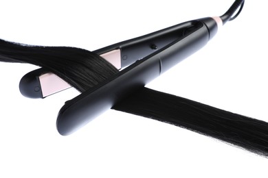 Photo of Straightener with black hair lock isolated on white