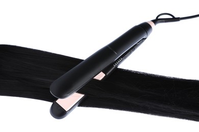 Photo of Straightener with black hair lock isolated on white