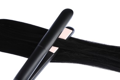 Photo of Straightener with black hair lock isolated on white