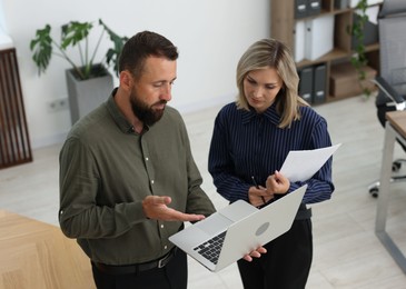 Photo of Business partners with laptop working together in office