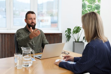 Photo of Business partners with laptop working together at table in office