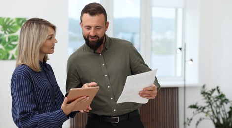 Photo of Smiling business partners with tablet working together in office