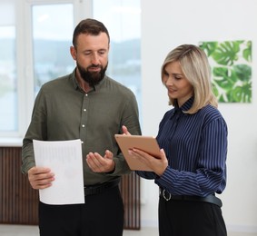 Photo of Smiling business partners with tablet working together in office