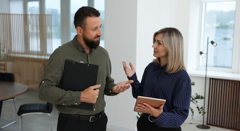 Photo of Smiling business partners with tablet and clipboard working together in office