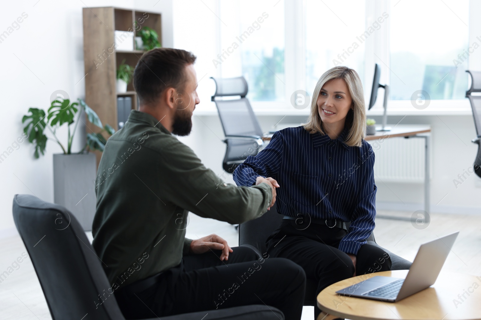 Smiling business partners shaking hands in office Photo of Smiling business partners shaking hands in office