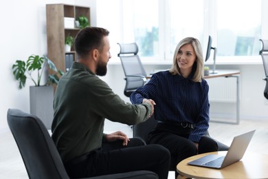 Photo of Smiling business partners shaking hands in office