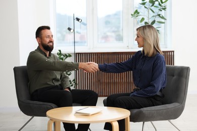 Photo of Smiling business partners shaking hands in office