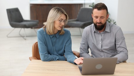 Photo of Business partners working with laptop at table in office