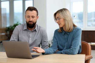 Photo of Business partners working with laptop at table in office