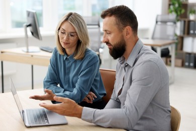 Photo of Business partners working with laptop at table in office