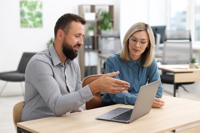Photo of Business partners working with laptop at table in office