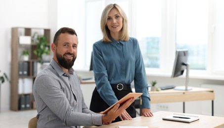 Photo of Portrait of smiling business partners with tablet at table in office