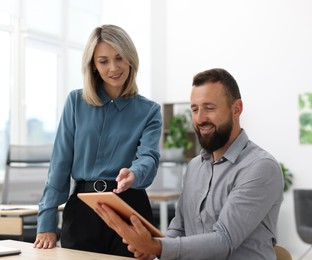 Photo of Smiling business partners working with tablet at table in office